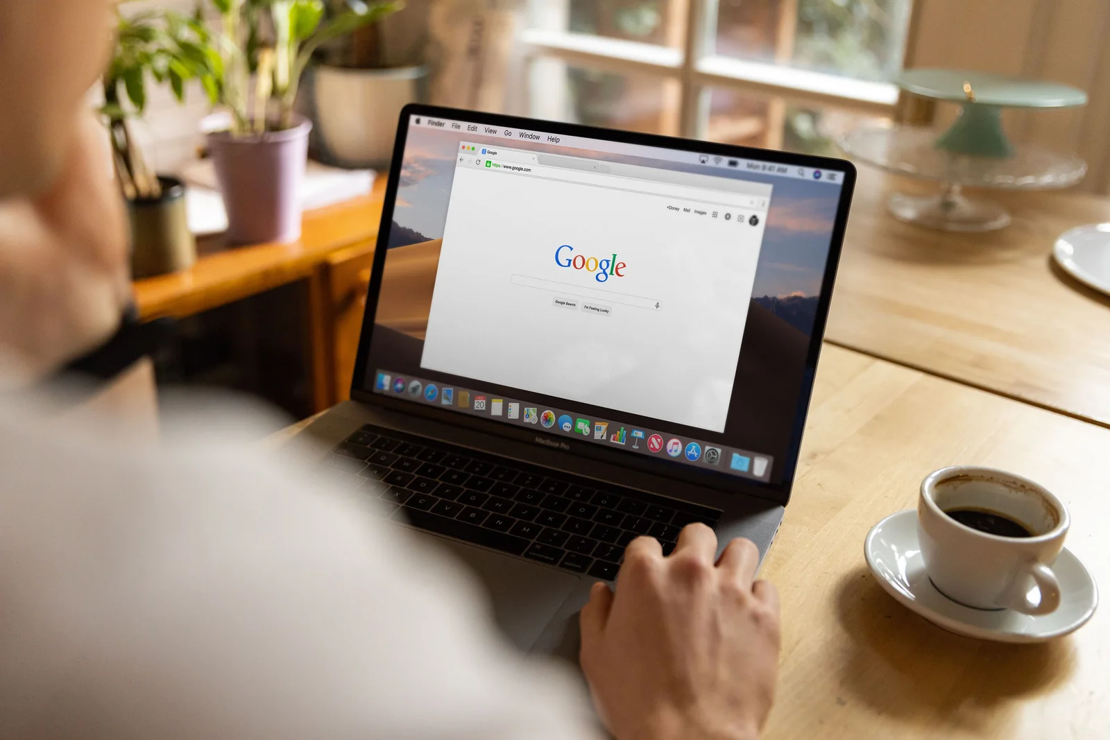 Person researching Google Search on a laptop beside a cup of coffee