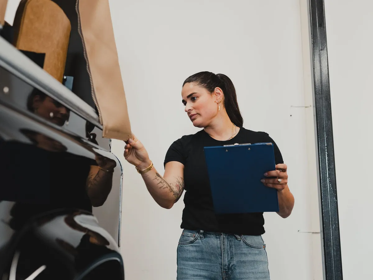 A shop team member with a clipboard checks over a customer's vehicle