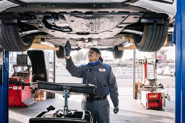 Auto repair technician inspecting the underside of a vehicle