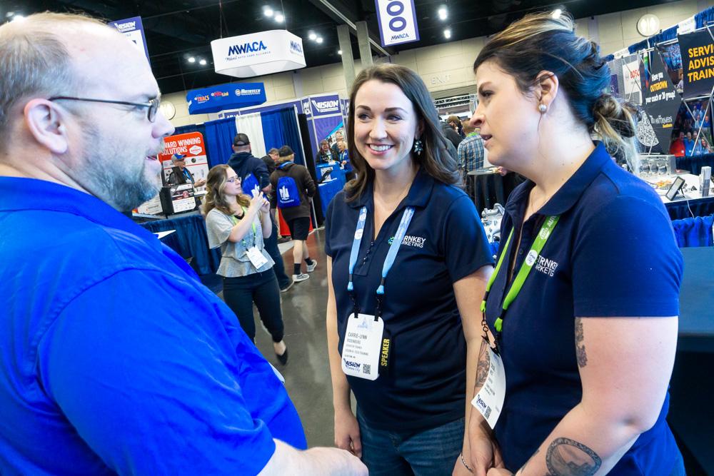 Turnkey Marketing team members talking with auto repair shop owners at VISION Hi-Tech Training & Expo