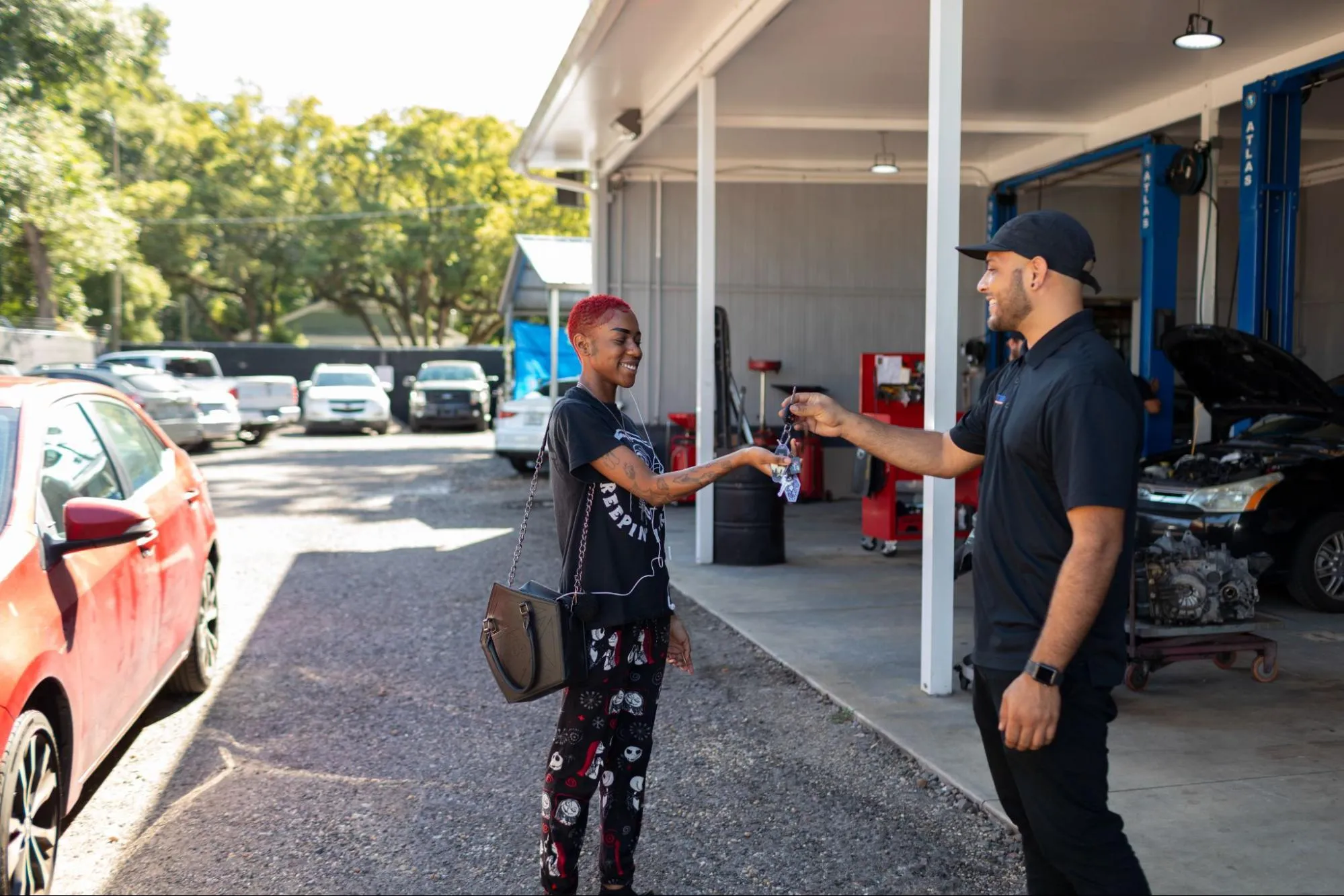 Auto repair technician handing car keys back to a smiling customer outside the shop